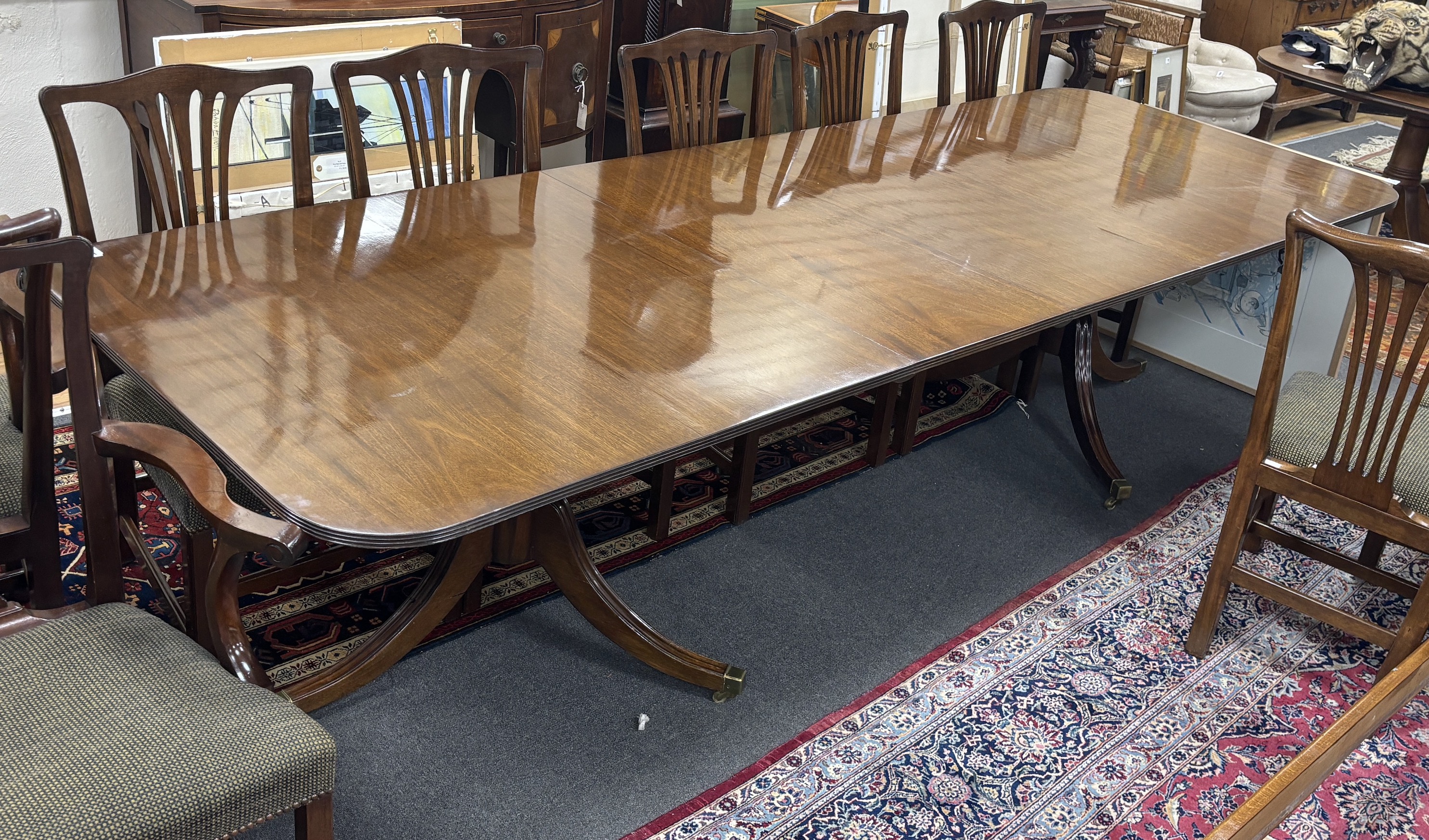 A reproduction George III style mahogany twin pillar extending dining table, 304cm extended, two spare leaves, depth 107cm, height 72cm